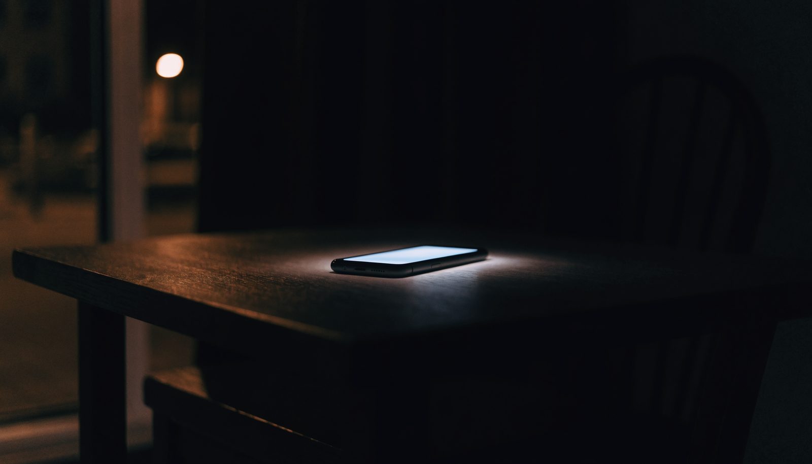 Téléphone allumé dans une pièce sombre, les arnaques à la voyance et les recours possibles