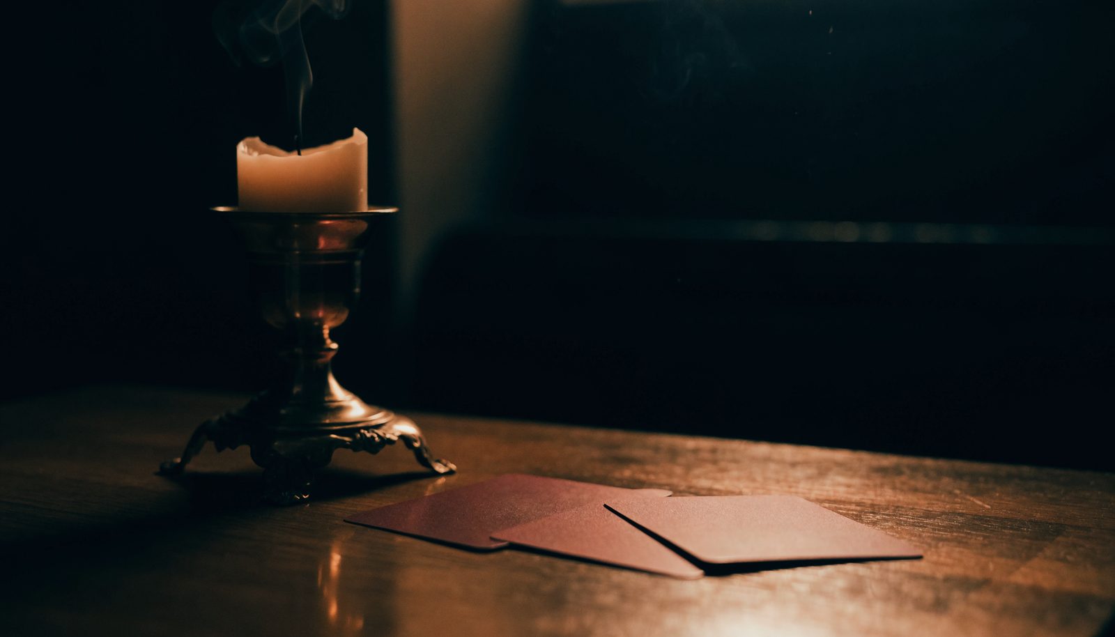 Bougie et cartes retournées sur une table sombre, les phrases qu'un voyant honnête ne dit jamais